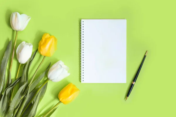 Komposition mit Notizbüchern, Papeterie und gelben Tulpen auf grünem Hintergrund mit Platz für Text — Stockfoto