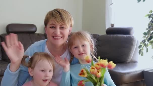 แม่ที่มีความสุขและเด็กผู้หญิงสองคนที่มีช่อดอกไม้โบกมือที่กล้อง . — วีดีโอสต็อก