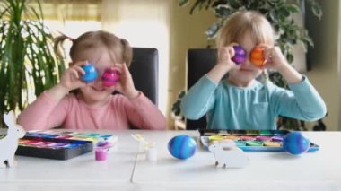 Mutlu anaokulu çocukları kameraya bakıp eğleniyorlar. Evde renkli Paskalya yumurtalarıyla çılgın komik suratlar yapıyorlar..