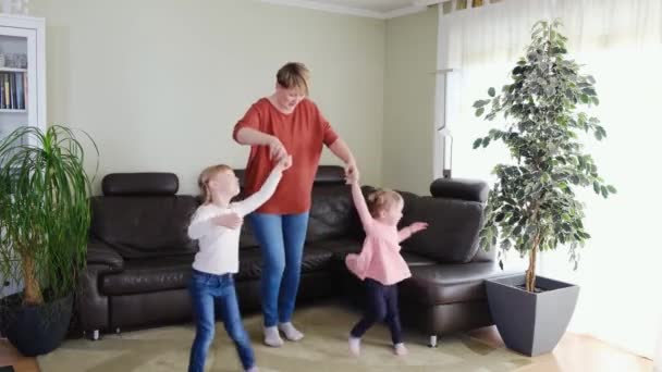 Mother nanny having fun with cute little girls dancing in living room. Happy family. — Stock Video