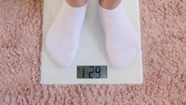 Woman legs in white socks stand on digital scales to check weight on floor in room. — 비디오