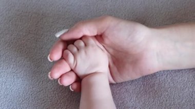 Anne yeni doğan bebeğinin elini tutuyor. Anneler sevgi ve bakım, çocukları koruma, evlat edinme, bebeklik konsepti.