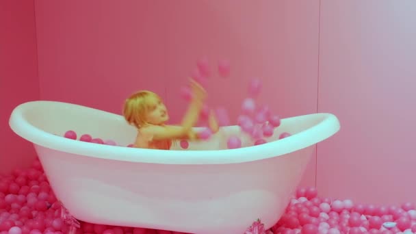Маленькая Счастливая Блондинка Кавказка Сидит Туалете Бросает Розовые Шарики Счастливого — стоковое видео