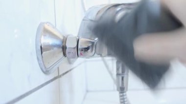 Lastik eldivenli bir kadın duş sulama tenekesini, banyoda lavaboyu temizliyor. Ev işi temizlik konsepti.