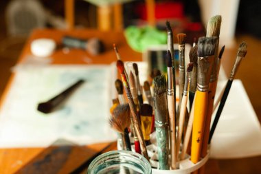 Profesyonel sanatçılar bir sanat atölyesinde boya kalıntılarıyla fırçalarlar..