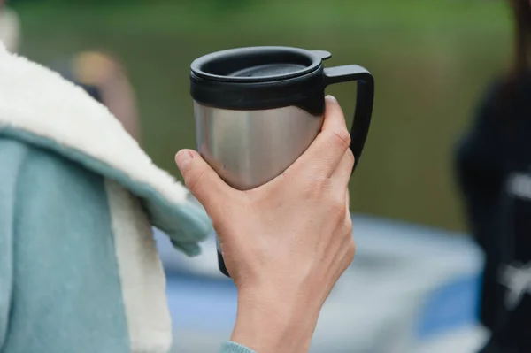 Reusable steel thermo mug in the girls hand for drinking throughout the day. ロイヤリティフリーのストック写真