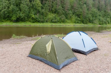 Alacakaranlıkta bir dağ nehrinin kıyısında iki çadır..