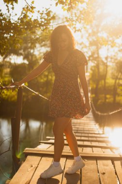 A white girl dances on a bridge during sunset. Enjoys evening rest.