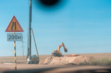 Ağır bir kazıcı, yol inşaatı ve destekleyici yapılar için araziyi geri istiyor.