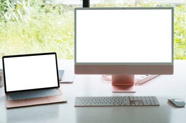 Modern çalışma masasında beyaz boş ekran monitörü ve laptop.