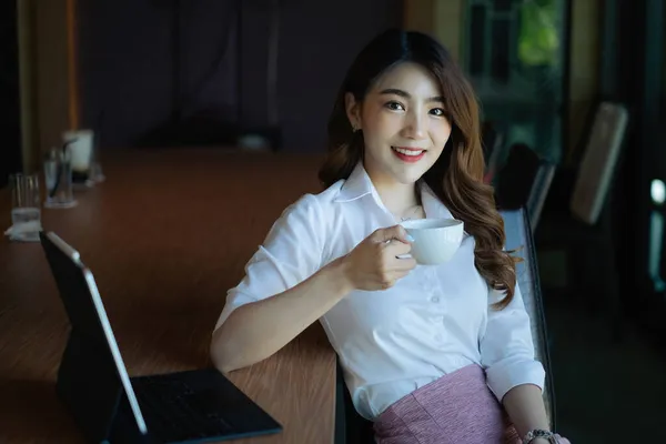Bild av vackra affärskvinna håller en kopp kaffe och kontrollerar hennes e-post innan du går till jobbet. — Stockfoto
