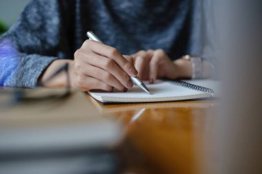 Genç bayan kolej notlar alıyor ve fosforlu kalem kullanıyor. Çevrimiçi sınıf odasında odaklanmış bir öğrenci. Otantik Eğitim kavramı.