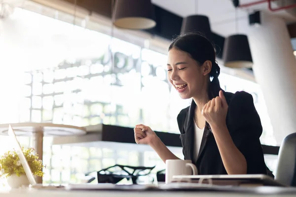 Izgalmas ázsiai üzletasszony ül az asztalnál, és ünnepli siker a munkahelyen — Stock Fotó