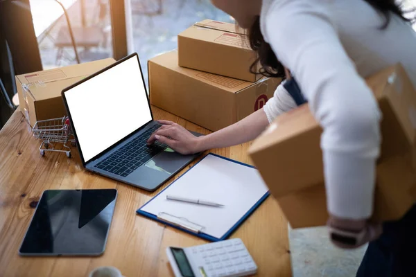 A tulajdonos ellenőrizze a vásárlói megrendeléseket a laptopjain és csomagolja be a termékeket otthon. Sikeres kkv-vállalkozói koncepció. — Stock Fotó