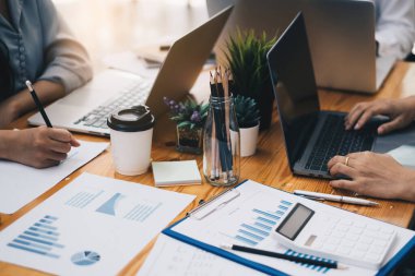 Analitik istihbarat konsepti. İş adamları grubu, toplantıda yatırım için dizüstü bilgisayarda mevcut mali ve ekonomik konuları tartışıyor.