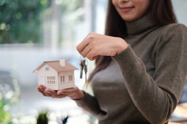 Bir emlakçı ev sigortası almak isteyen müşterilere House modelini gösteriyor. Ev sigortası ve mülk kavramı.