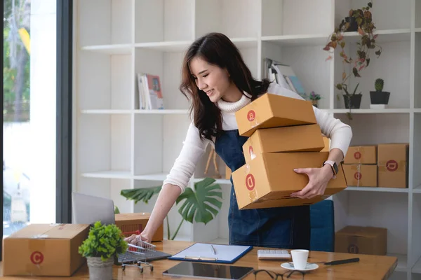 Kleinunternehmerin mit Paketkasten und arbeitet bei ihr zu Hause, um Bestellungen zu verpacken, bevor sie sie an den Kunden schickt. Freiberufliches Arbeiten und KMU-Unternehmerkonzept. — Stockfoto