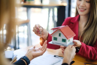 Ev almak için anlaşma imzaladıktan sonra iş kadınının ev anahtarını vermesine yakın çekim. Banka müdürü ve emlak konsepti.