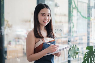 Kafe açıkken kafe sahibi kadının portresi gülümsüyor. KOBİ girişimci iş konsepti.