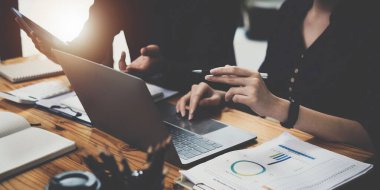 Analitik istihbarat konsepti. İş adamları grubu, toplantıda yatırım için dizüstü bilgisayarda mevcut mali ve ekonomik konuları tartışıyor.