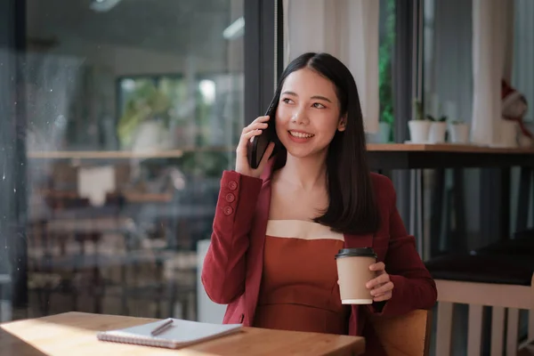 Mujer de negocios discutiendo con su equipo por teléfono móvil mientras relexing en la cafetería. Concepto financiero. — Foto de Stock