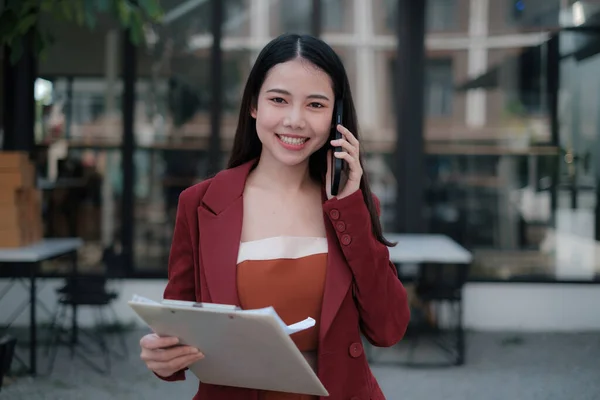Sonriente y feliz mujer de negocios asiática hablando con el teléfono móvil. Concepto de finanzas y contabilidad. — Foto de Stock