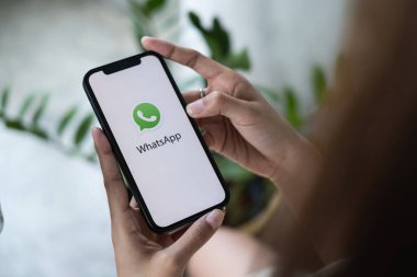 CHIANG MAI, THAILAND - 16 HAZİRAN 2022: Bir kadın iPhone tutuyor ve ekranda sosyal internet servisi WhatsApp 'ı arıyor. iPhone Apple tarafından oluşturuldu ve geliştirildi.