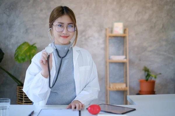 Portrait of doctor smiling wearing eyeglasses and showing stethoscope tools at office in private clinic. Medicine and health care and insurance concept. — Stock Photo, Image