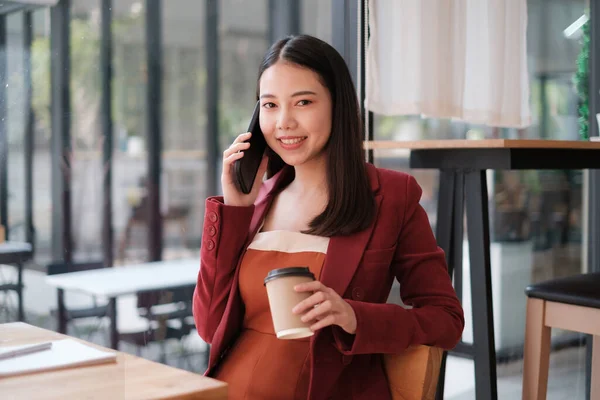 Mujer de negocios discutiendo con su equipo por teléfono móvil mientras relexing en la cafetería. Concepto financiero. — Foto de Stock