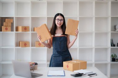 Asyalı küçük işletme sahibi ev ofisinde çalışıyor. Ticari perakende pazarı ve çevrimiçi pazarlama dağıtımı, KOBİ e-ticaret kavramı.