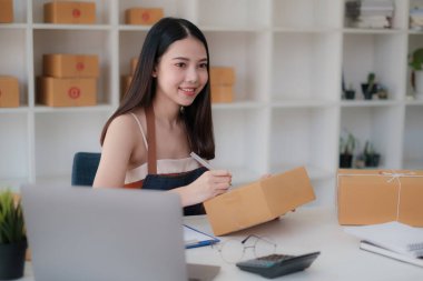 Asyalı küçük işletme sahibi ev ofisinde çalışıyor. Ticari perakende pazarı ve çevrimiçi pazarlama dağıtımı, KOBİ e-ticaret kavramı.