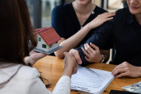 A happy young couple receives a wonderful bargain after signing a contract to purchase a home. Broker and customer shake hand after have a good deal. Real Estate concept. — Stock Photo, Image