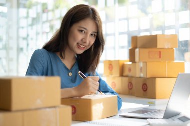 Asyalı küçük işletme sahibi ev ofisinde çalışıyor. Ticari perakende pazarı ve çevrimiçi pazarlama dağıtımı, KOBİ e-ticaret kavramı.