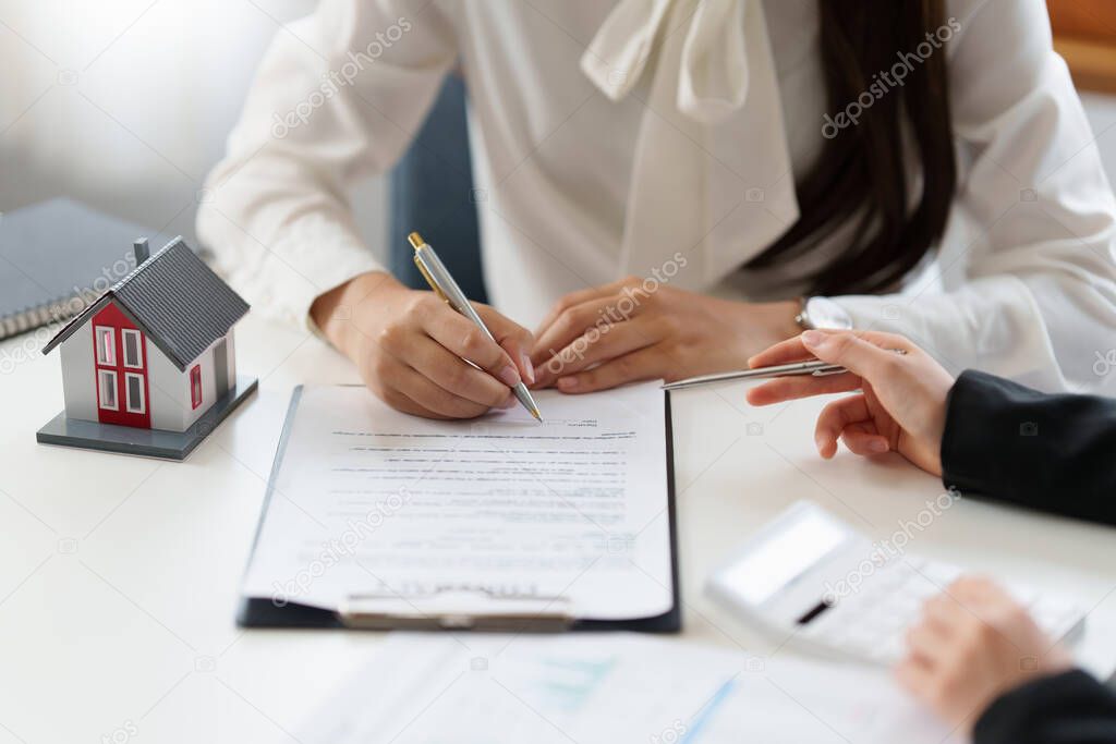 Close up of Business woman pointing and signing agreement for buying house. Bank manager concept.