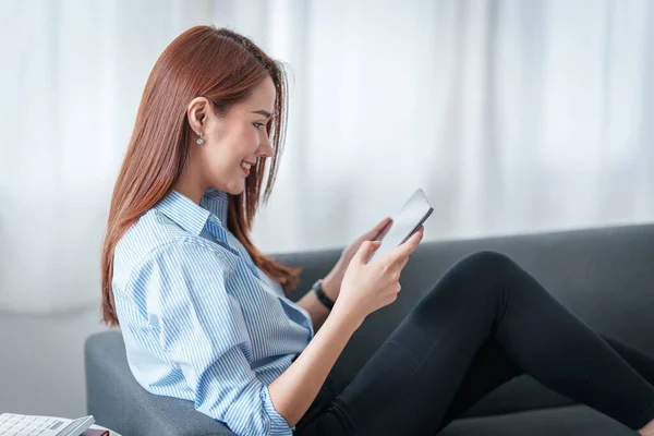 Γυναίκα απολαμβάνουν με περιεχόμενο streaming ταινίες ή εφαρμογή κοινωνικών μέσων μαζικής ενημέρωσης σε ψηφιακό tablet κάθεται στον καναπέ στο σπίτι. — Φωτογραφία Αρχείου