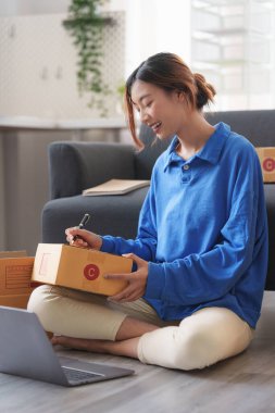 Asyalı küçük işletme sahibi ev ofisinde çalışıyor. Ticari perakende pazarı ve çevrimiçi pazarlama dağıtımı, KOBİ e-ticaret kavramı.