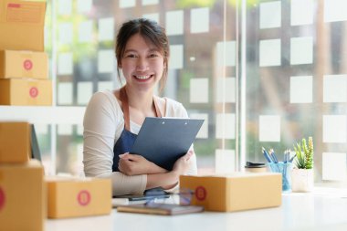 Asyalı küçük işletme sahibi ev ofisinde çalışıyor. Ticari perakende pazarı ve çevrimiçi pazarlama dağıtımı, KOBİ e-ticaret kavramı.