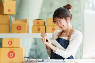 Asyalı küçük işletme sahibi ev ofisinde çalışıyor. Ticari perakende pazarı ve çevrimiçi pazarlama dağıtımı, KOBİ e-ticaret kavramı.