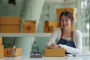 Asyalı küçük işletme sahibi ev ofisinde çalışıyor. Ticari perakende pazarı ve çevrimiçi pazarlama dağıtımı, KOBİ e-ticaret kavramı.