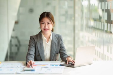 Çekici Asyalı İş Kadını ofiste müşteriyle cep telefonuyla konuşuyor..