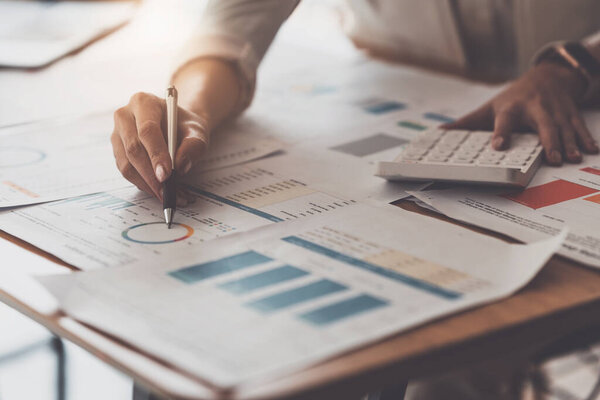 Закройте руку деловой женщины с помощью калькулятора для расчета финансовых результатов и бюджета компании. Концепция аудита счетов.