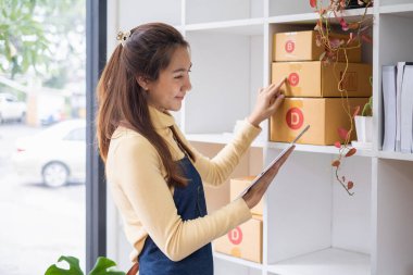 Asyalı küçük işletme sahibi ev ofisinde çalışıyor. Ticari perakende pazarı ve çevrimiçi pazarlama dağıtımı, KOBİ e-ticaret kavramı.