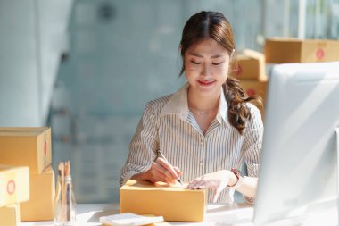 Asyalı küçük işletme sahibi ev ofisinde çalışıyor. Ticari perakende pazarı ve çevrimiçi pazarlama dağıtımı, KOBİ e-ticaret kavramı.