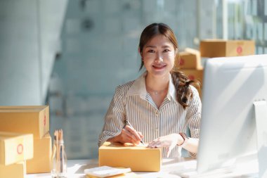 Asyalı küçük işletme sahibi ev ofisinde çalışıyor. Ticari perakende pazarı ve çevrimiçi pazarlama dağıtımı, KOBİ e-ticaret kavramı.
