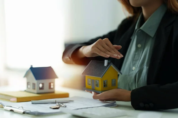 Kobieta trzyma i sprawdza model domu.Nieruchomości Dom Wycena i inspekcja i koncepcja ubezpieczenia. — Zdjęcie stockowe