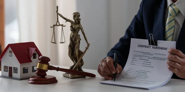 Lawyer in the office with brass scale and pointing in contract on wooden table. Justice and law concept. — Zdjęcie stockowe