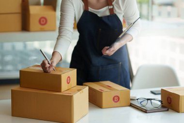 Asyalı küçük işletme sahibi ev ofisinde çalışıyor. Ticari perakende pazarı ve çevrimiçi pazarlama dağıtımı, KOBİ e-ticaret kavramı.