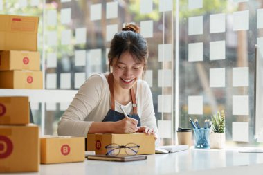 Asyalı küçük işletme sahibi ev ofisinde çalışıyor. Ticari perakende pazarı ve çevrimiçi pazarlama dağıtımı, KOBİ e-ticaret kavramı.