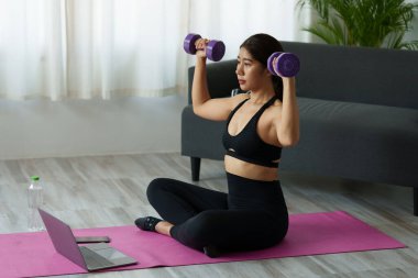 Evde halterlerle egzersiz yapan güzel bir kadın. Vücut geliştirme, fitness, spor, halter kavramı.