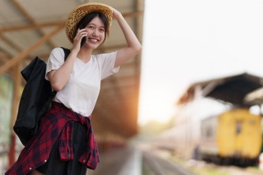 Genç gezgin kadın tren istasyonunda arkadaş planlama gezisi arıyor. Yaz ve seyahat yaşam tarzı konsepti.